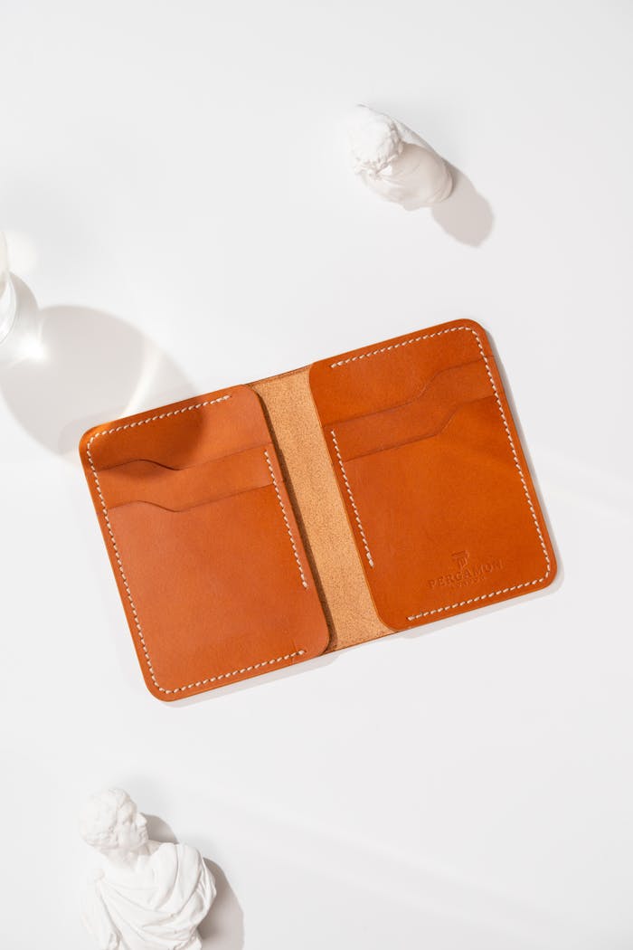 Open tan leather wallet displayed on a clean white background.